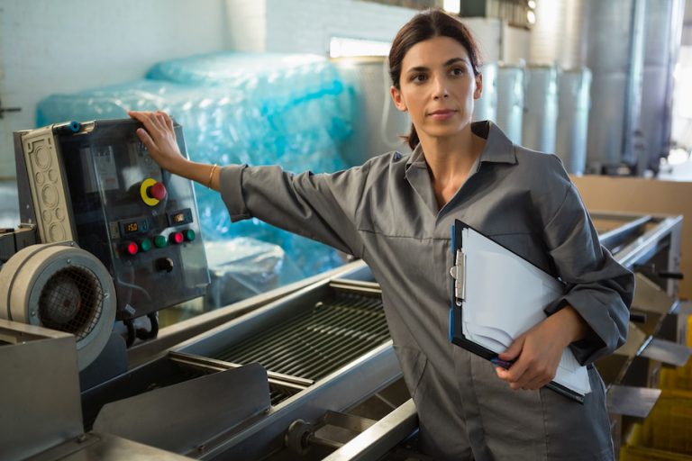 Woman with clipboard standing near machine in olive factory